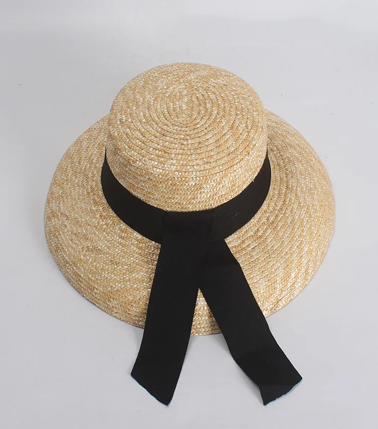 Elegant French-style straw sun hat with a wide brim and a black ribbon tied around the crown.