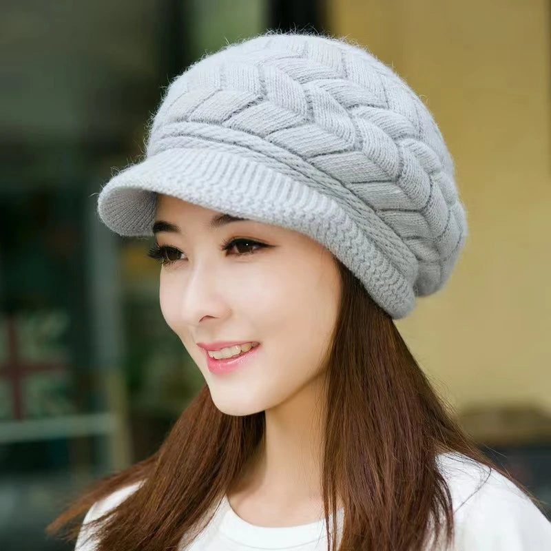 A woman wearing a light grey, thermal knitted peaked beanie with a stylish herringbone texture.