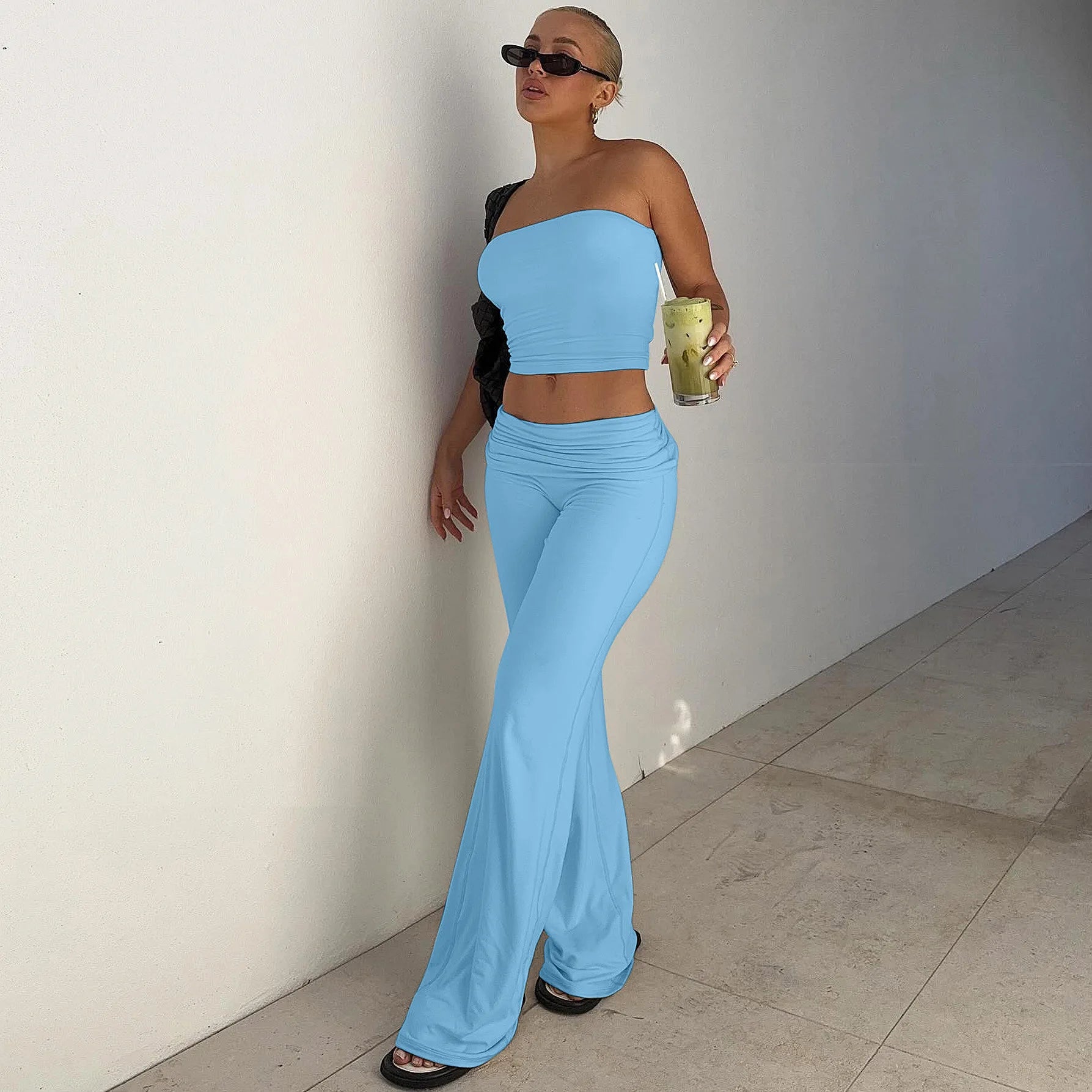 Woman wearing a sky-blue, two-piece set featuring a strapless crop top and matching high-waisted wide-leg trousers.