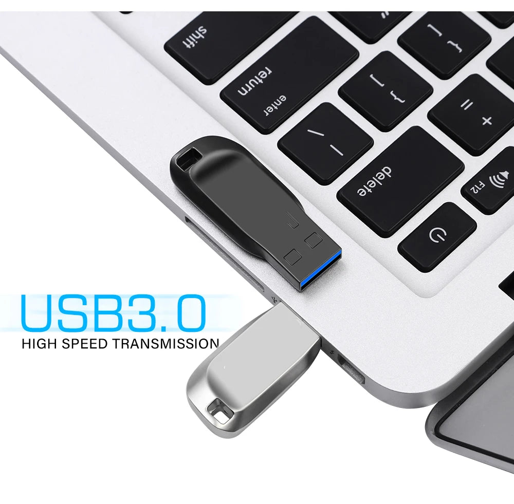 Sleek black and silver metal USB 3.0 flash drives plugged into a laptop keyboard.