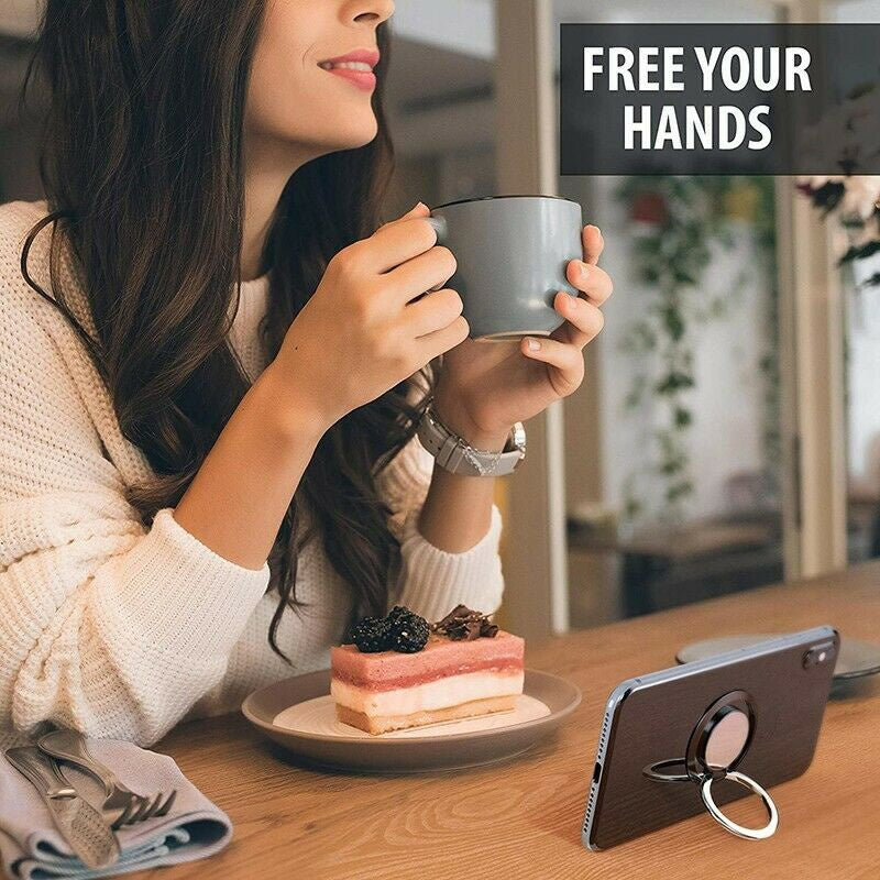 A dark wood-finish phone case with a circular silver ring stand, propping a smartphone up on a wooden table.