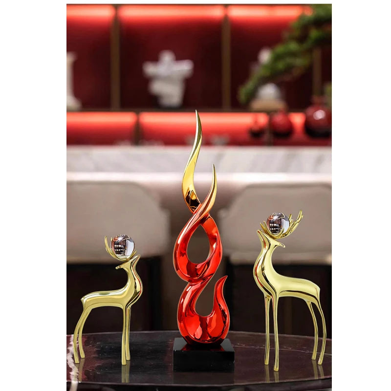 Modern resin ornament set featuring two gold deer with crystal spheres and a central red and gold flame-style sculpture.