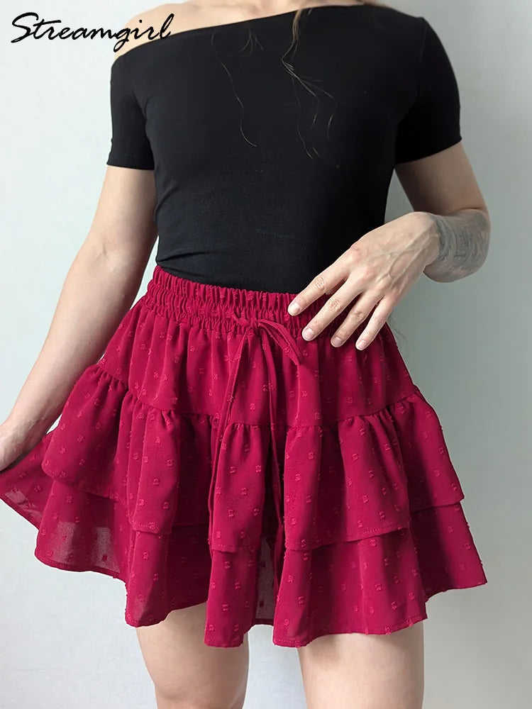 Red A-line mini skirt with layered ruffles, elastic tie-up waistband, and textured dotted fabric.