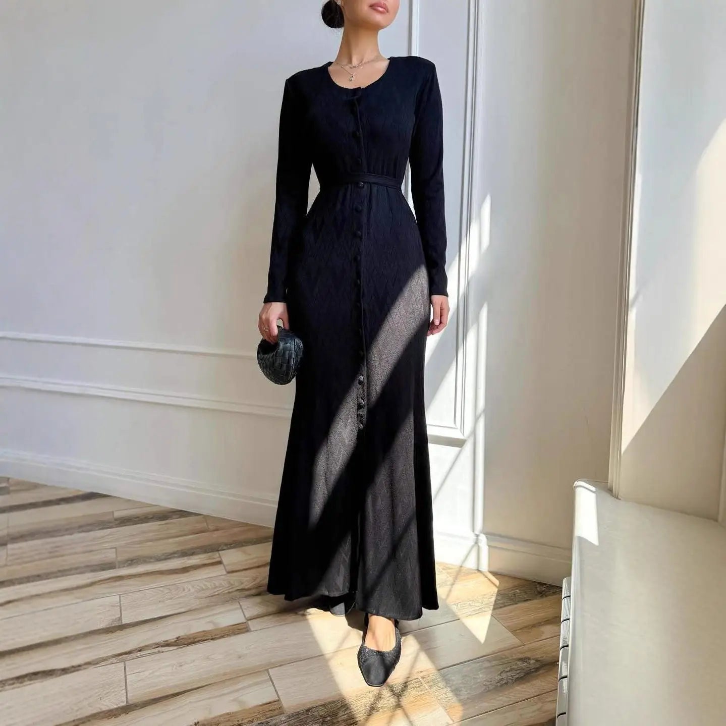 Black long-sleeved maxi dress with a button-front, fitted waist, and subtle textured pattern.