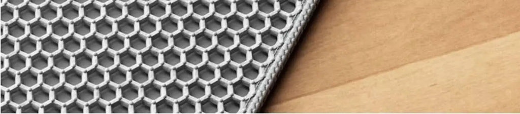 Grey waterproof cat litter mat with a textured honeycomb surface design, resting on a light wood floor.
