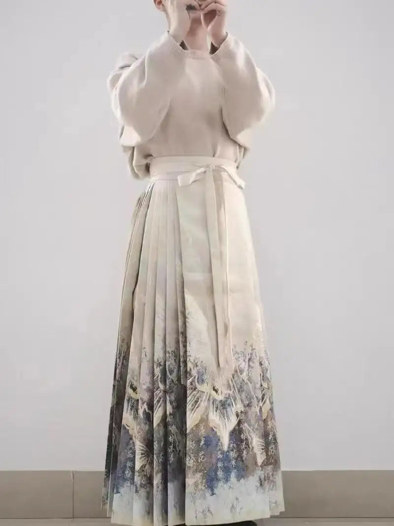 Beige pleated maxi skirt with a wrap-around tie waist and a scenic landscape print at the hem.