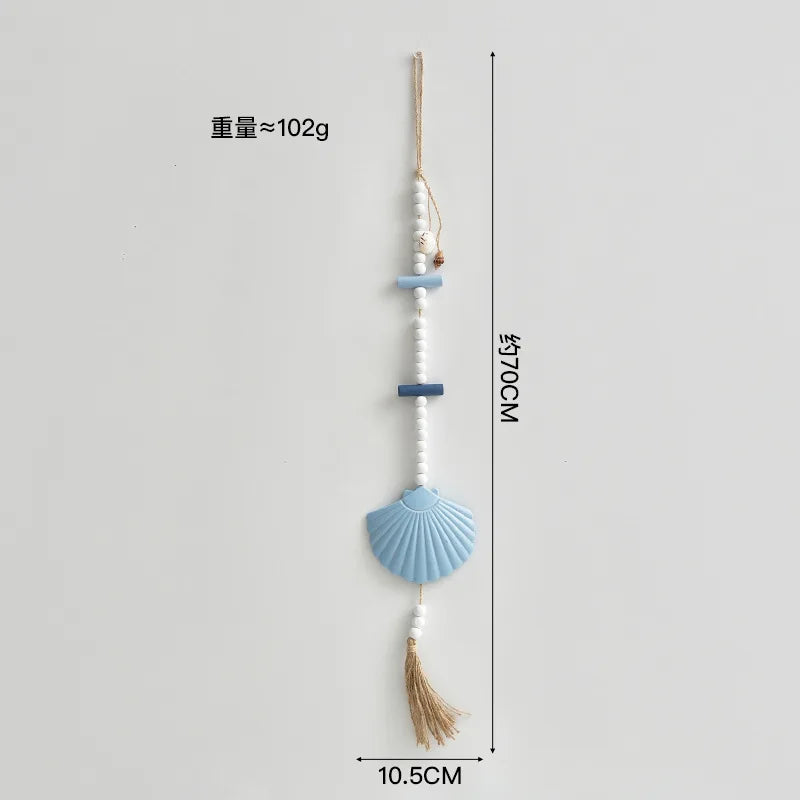 Boho wall hanging with a blue shell feature, white beads, blue wooden accents, and a jute tassel. 70cm length.