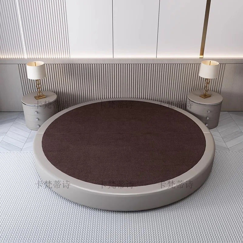 A modern, minimalist circular bed frame with a dark brown upholstered top and a light grey padded surround.