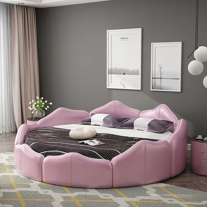 A luxury round pink faux leather bed frame with a distinctive petal-shaped headboard and curved cushioned surround.