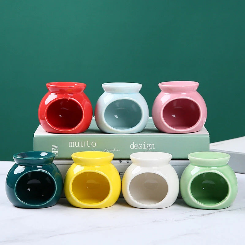 Seven colourful, round ceramic oil burners for wax melts in red, blue, pink, dark green, yellow, white, and sage.