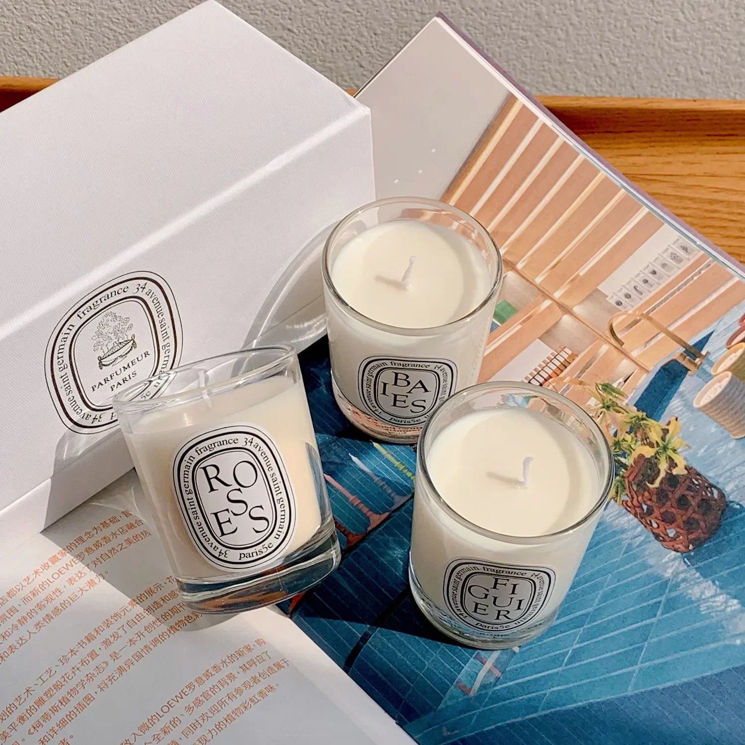 Three clear glass scented candles with white wax and iconic oval black-and-white labels, displayed with a gift box.