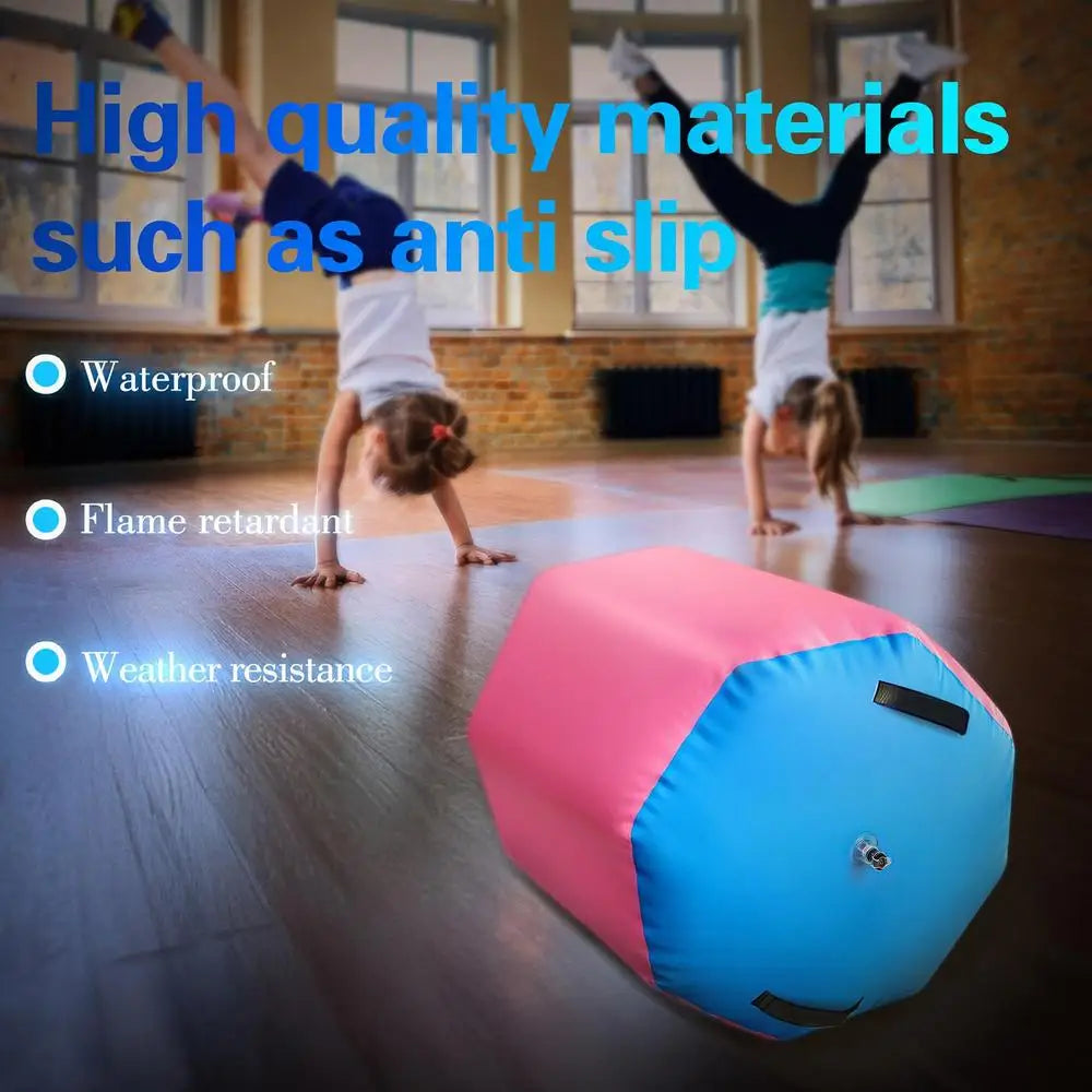 A pink and blue inflatable gymnastics training barrel with a central valve, positioned on a wooden studio floor.