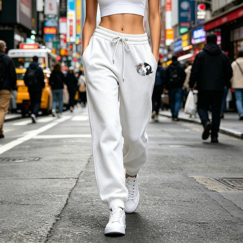White high-waisted joggers featuring a drawstring waist and a small black and white koi fish graphic on the hip.