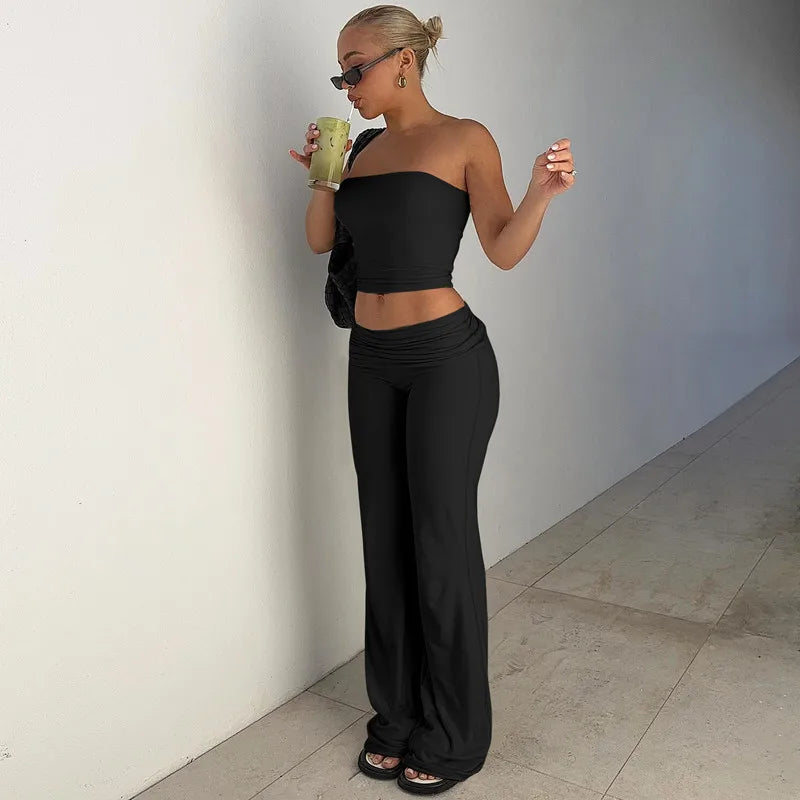 Woman wearing a black two-piece set featuring a strapless cropped top and high-waisted wide-leg trousers.