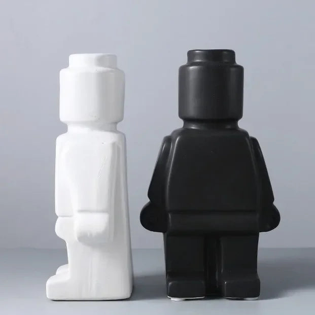 Two minimalist ceramic vases shaped like blocky toy figures in matte white and black.