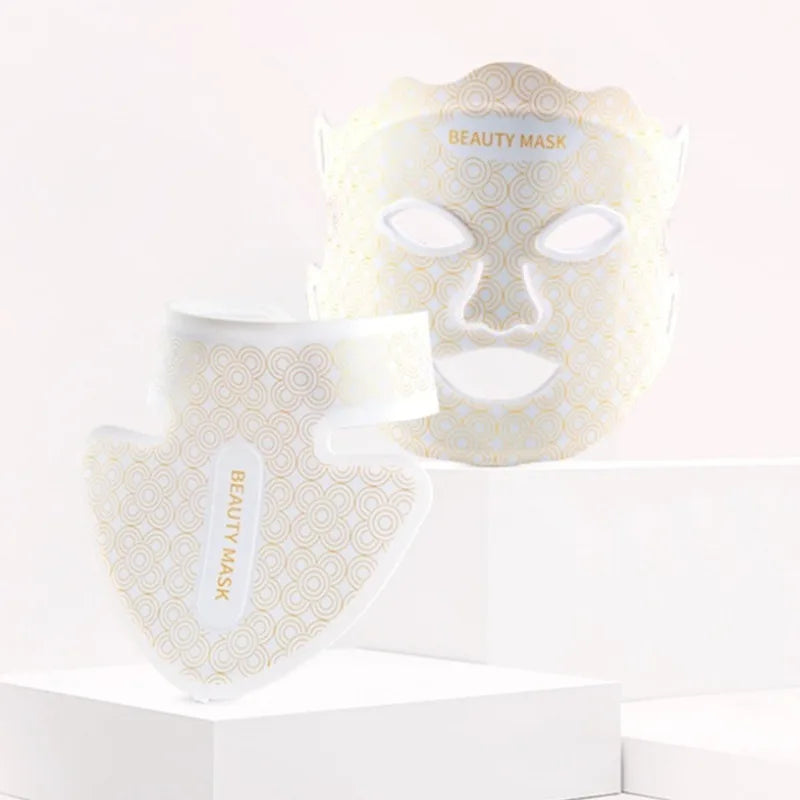 White beauty mask and neck piece with gold geometric patterns on white pedestals.