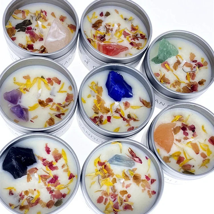 Top-down view of seven silver tin candles, each featuring white wax topped with dried flower petals and unique crystals.