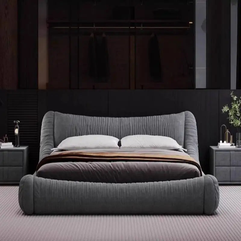 Modern grey fabric bed frame with a textured, curved headboard and matching side tables in a contemporary bedroom.