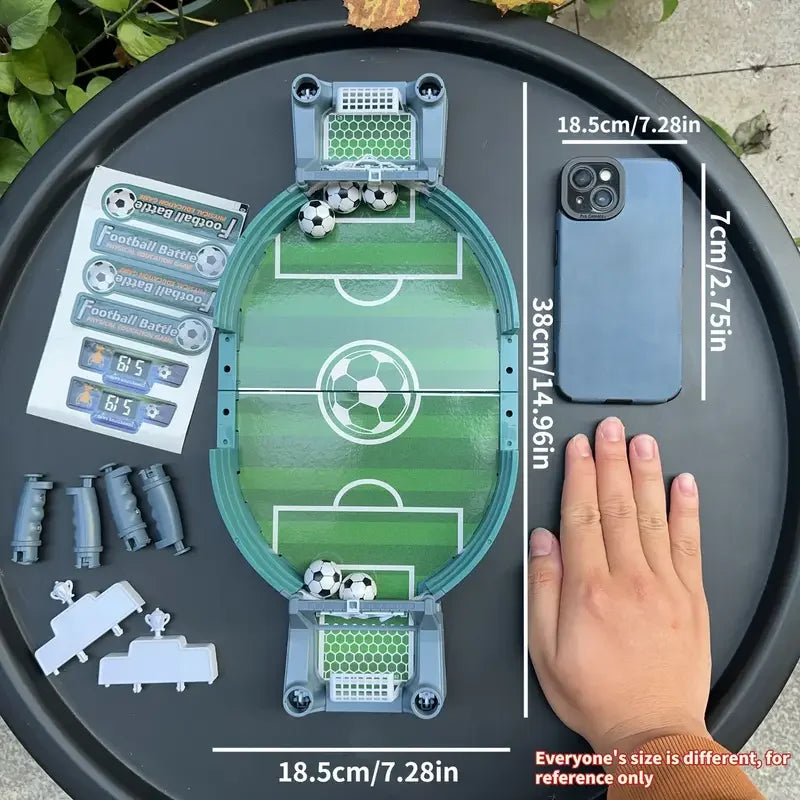Compact tabletop football game set with green pitch, goal nets, four mini balls, and stickers on a black surface.