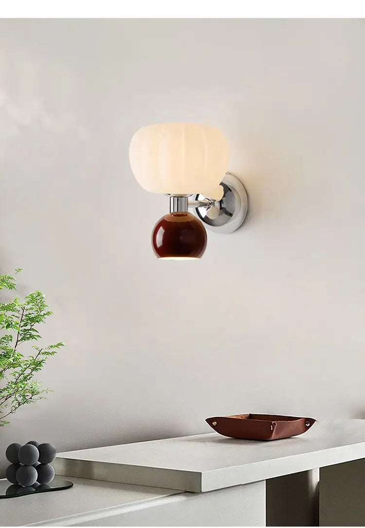 A modern cream-style wall lamp featuring a ribbed white glass shade, a glossy brown orb base, and chrome detailing.