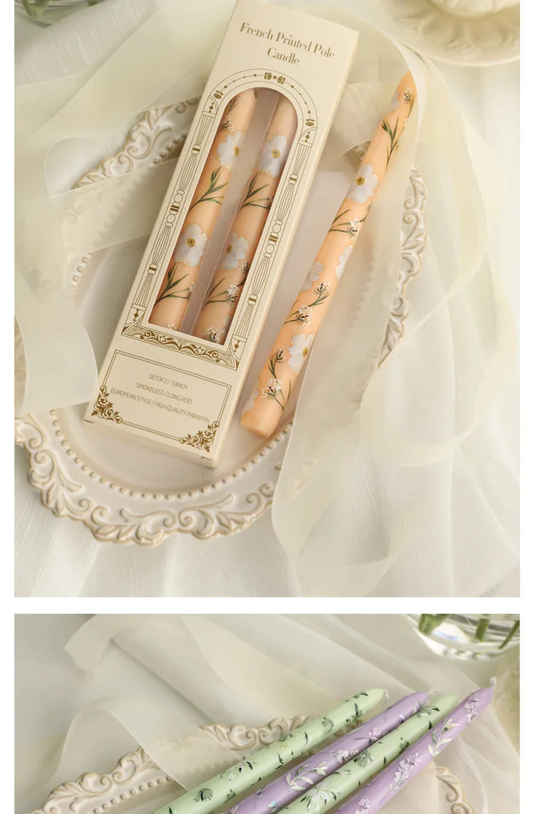 Set of two elegant, pale peach taper candles with delicate white floral prints, presented in a vintage-style box.