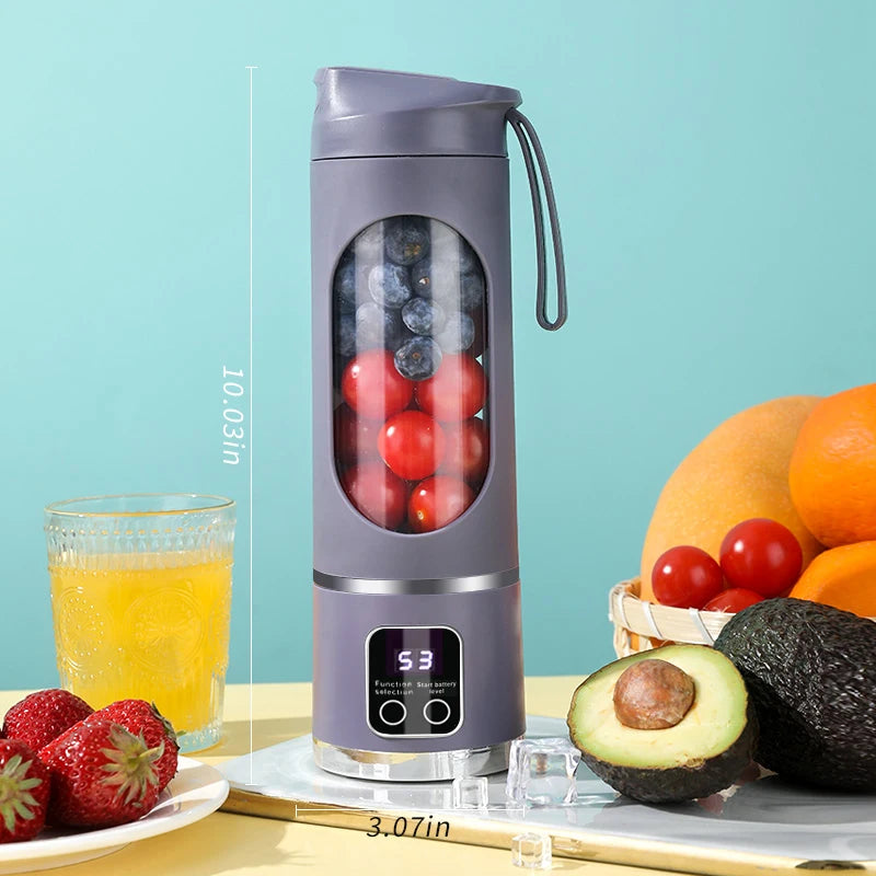 Grey portable blender bottle with a digital battery display, containing blueberries and tomatoes on a kitchen table.