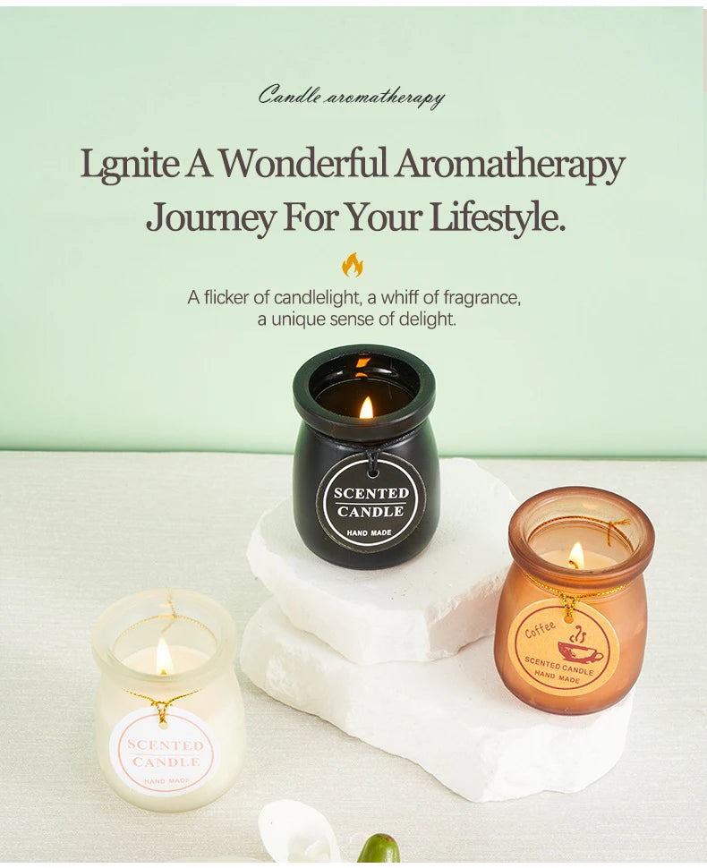 Three lit, handmade scented candles in small jar-style glass holders, featuring white, black, and amber colours.
