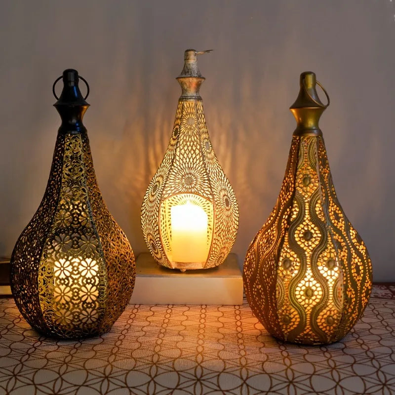Three teardrop-shaped Moroccan iron lanterns with intricate hollow cutouts, glowing with lit candles inside.