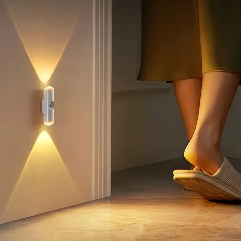 Modern white rechargeable LED wall light with motion sensor casting a warm, dual-directional beam.