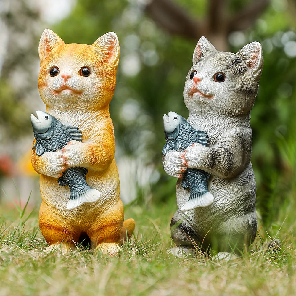 Two charming resin cat garden statues, one orange and one grey, each standing and holding a small blue fish.