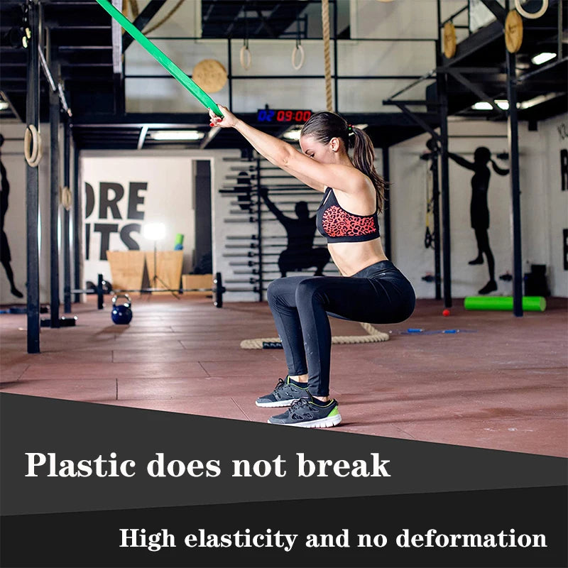 A person performing a squat in a gym, holding a durable, bright green flat resistance band for training.
