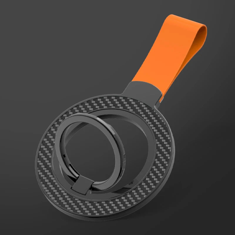 Circular carbon-fiber phone ring holder with an orange silicone strap on a dark gray background.