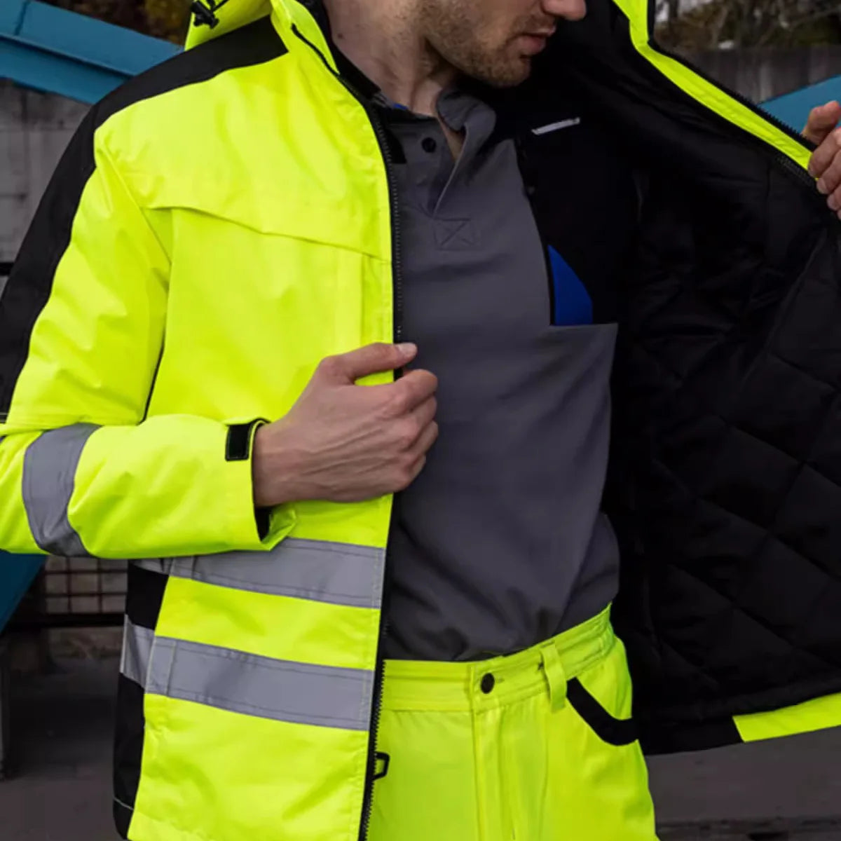 Man wearing a hi-vis yellow and black waterproof 3-in-1 jacket and trousers set with reflective tape strips.