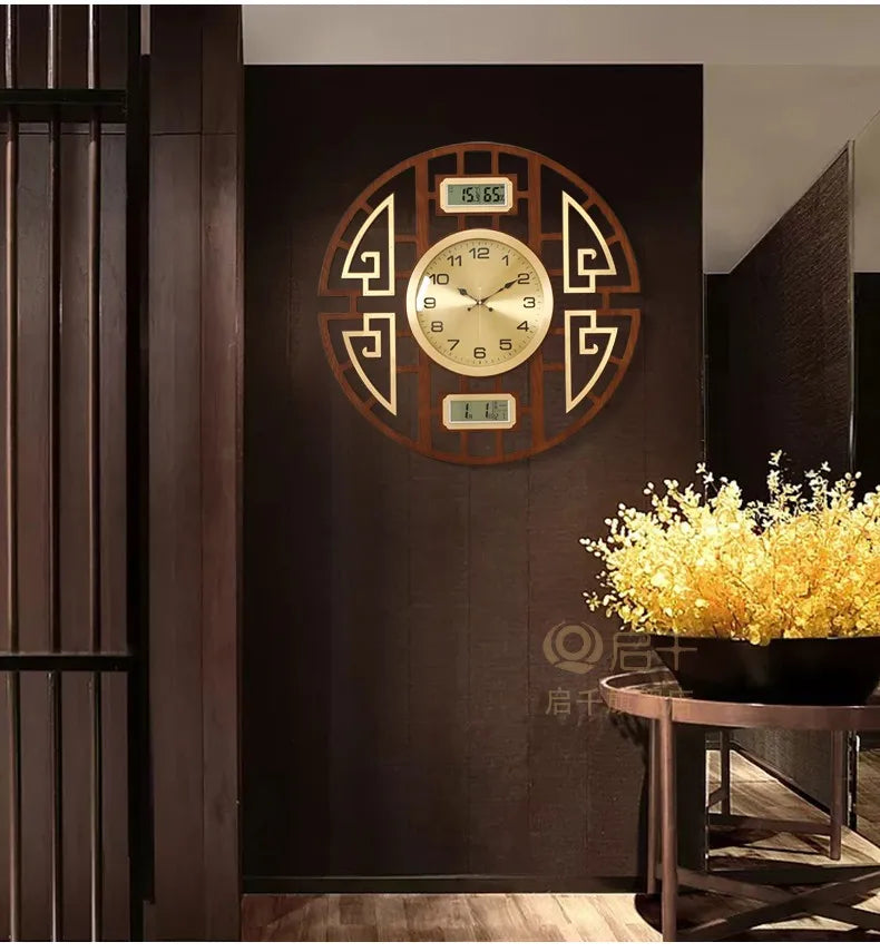 Round wall clock with a dark wooden frame, gold centre dial, and two digital displays, mounted on a dark feature wall.