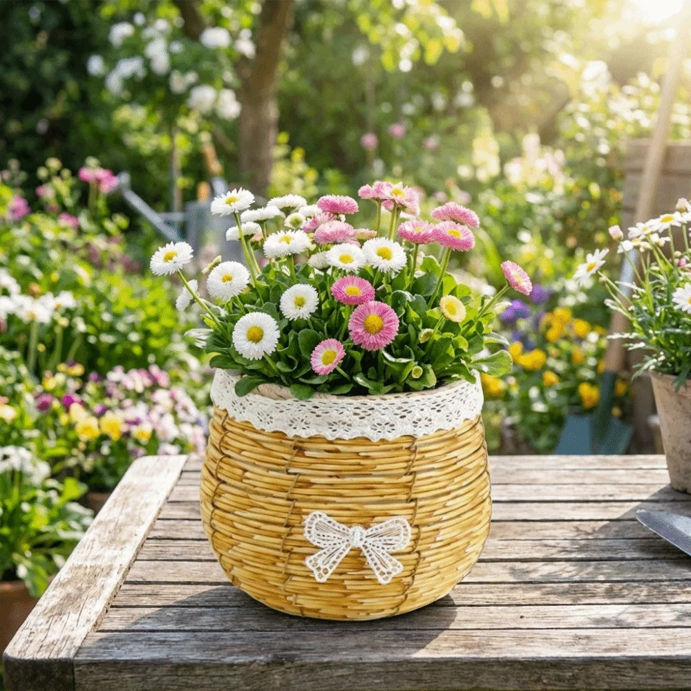 A rustic woven basket, adorned with a white lace trim and bow, filled with pink and white daisies on a wooden table.