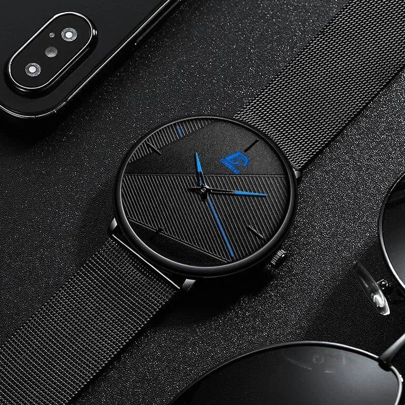 Minimalist men’s ultra-thin black wristwatch with a mesh strap, textured dial and striking blue hands.
