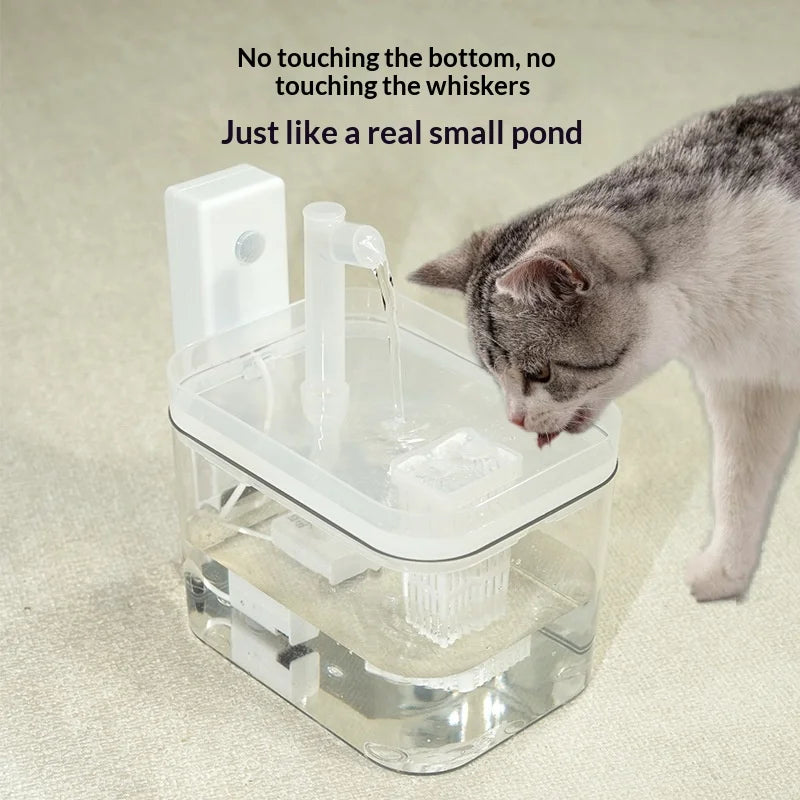 White automatic pet water fountain with a clear tank, integrated filter, and motion sensor, being used by a cat.