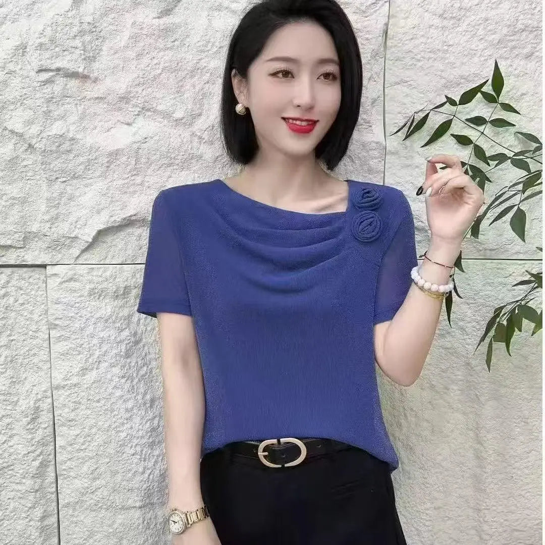 Blue short-sleeve blouse with a draped cowl neckline and decorative floral detail on the shoulder.
