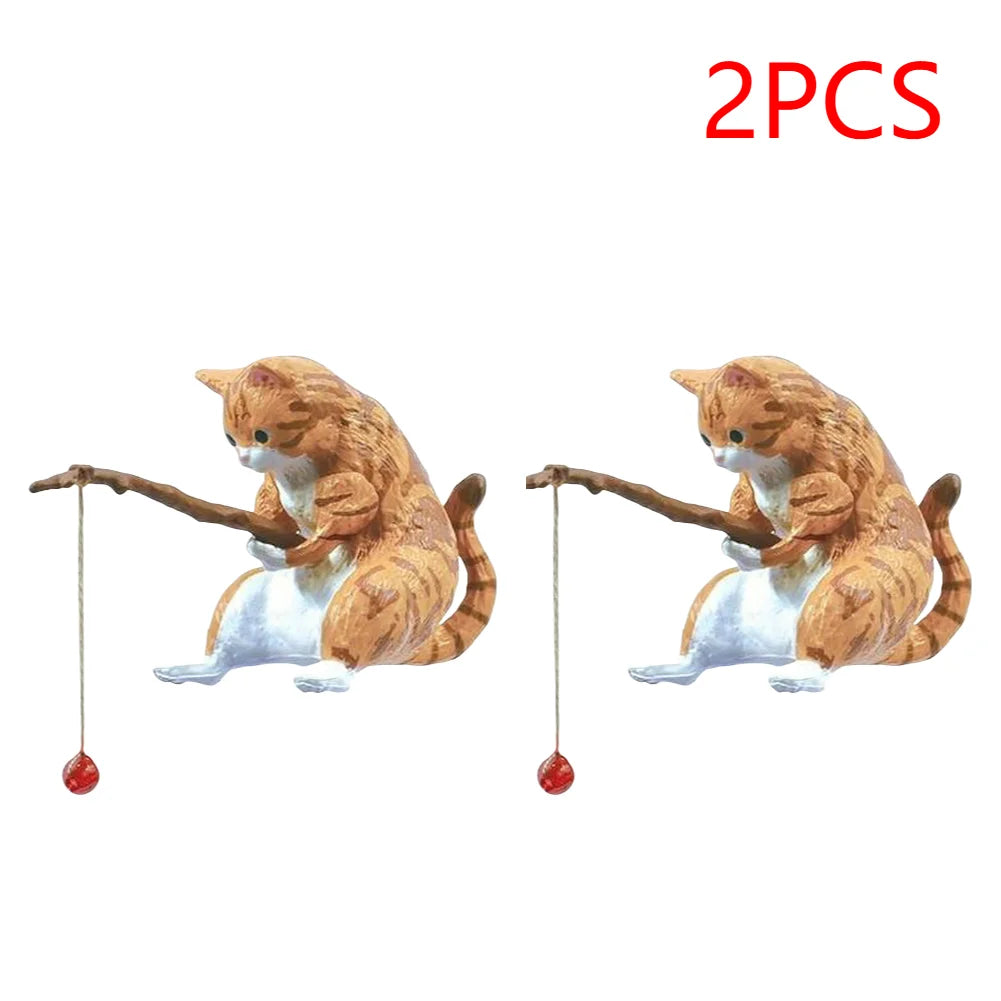 Two orange tabby cat aquarium ornaments, each sitting and holding a miniature fishing rod with a small red bobber.
