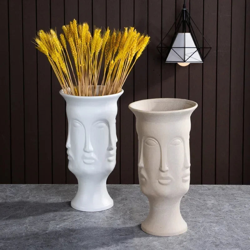 Two tall ceramic vases in white and cream, each featuring a unique multi-face sculptural design.