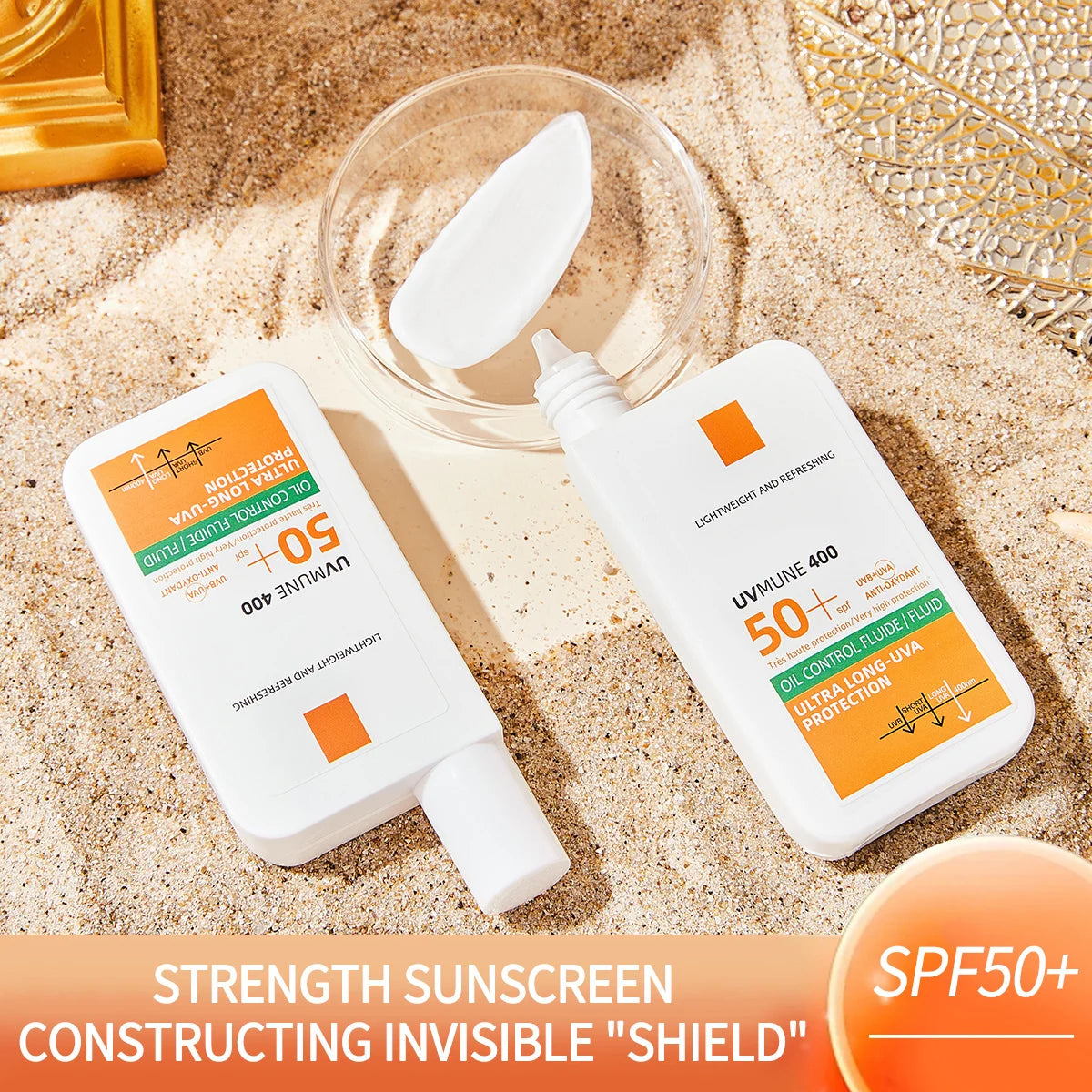 Two white, rectangular SPF 50+ sunscreen bottles with orange accents, shown on sand with a dollop of cream.