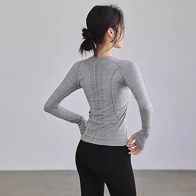 Women’s grey long-sleeve gym top featuring seamless breathable detailing and thumbhole cuffs, shown from the back.