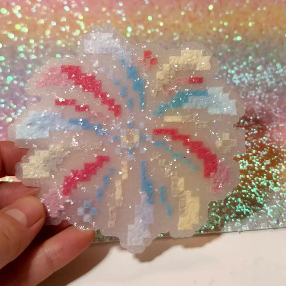 Sparkling resin coaster shaped like a firework, featuring pastel pink, blue, and yellow pixel-art style patterns.