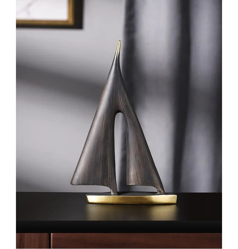 Abstract resin sailboat ornament in dark, textured bronze with a smooth gold-coloured base.