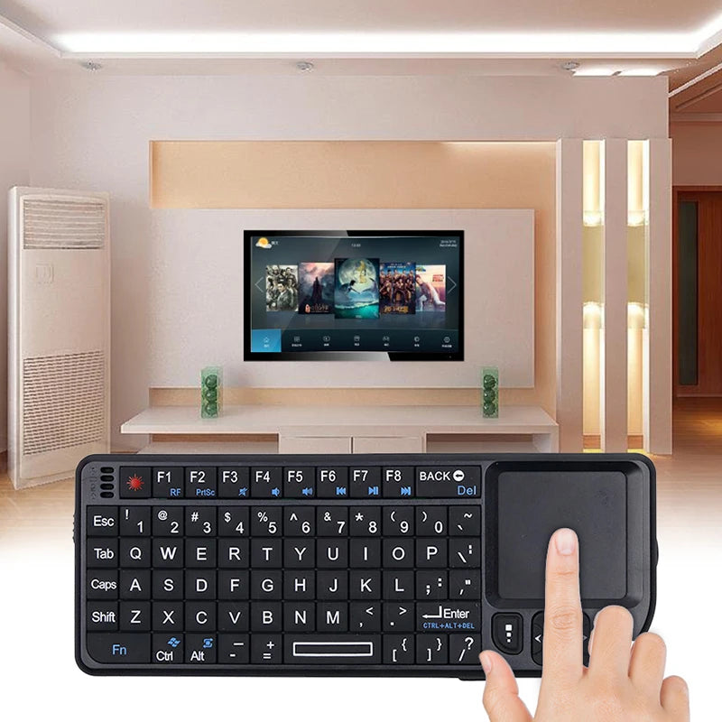 Small black plastic wireless keyboard with QWERTY keys and a built-in touchpad being used by a hand.