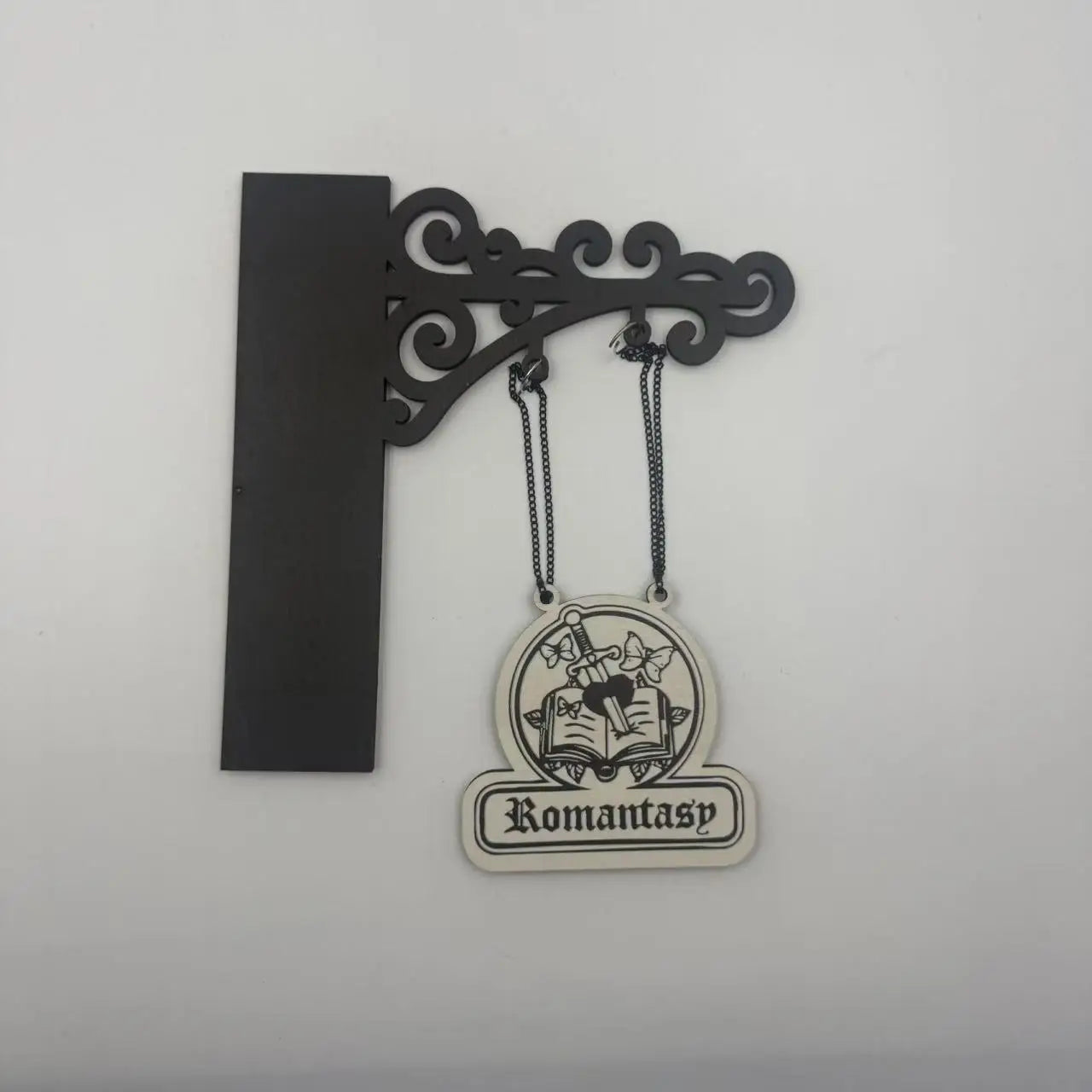 Decorative black wall bracket hanging a cream-coloured sign with a 'Romantasy' book, sword, and butterfly design.
