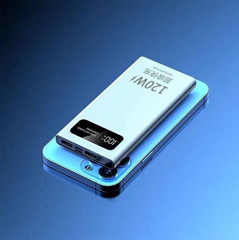 Silver portable power bank with a digital percentage display, resting on a smartphone against a blue background.
