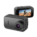 Black plastic action camera with front lens and rear screen displaying a motorcycle in the desert.
