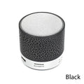 Portable black mini cylindrical Bluetooth speaker with a textured finish, silver speaker grille, and USB/SD card slots.