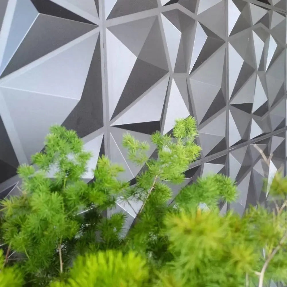 Modern 3D geometric wall panels in shades of grey and black, featuring a textured diamond design with a green plant.